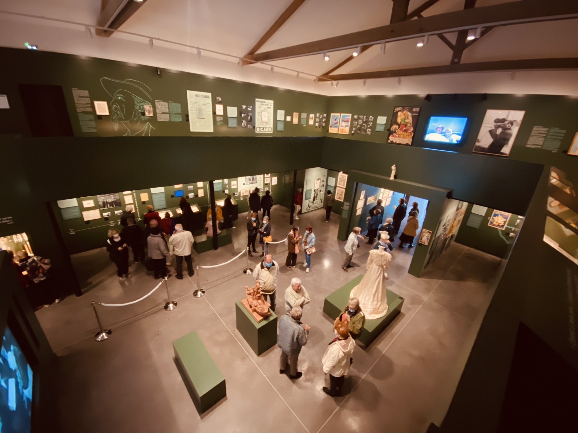 Vue plongeante de l'intérieur du Musée Paul Ricard avec visiteurs, panneaux d'exposition et sculptures.