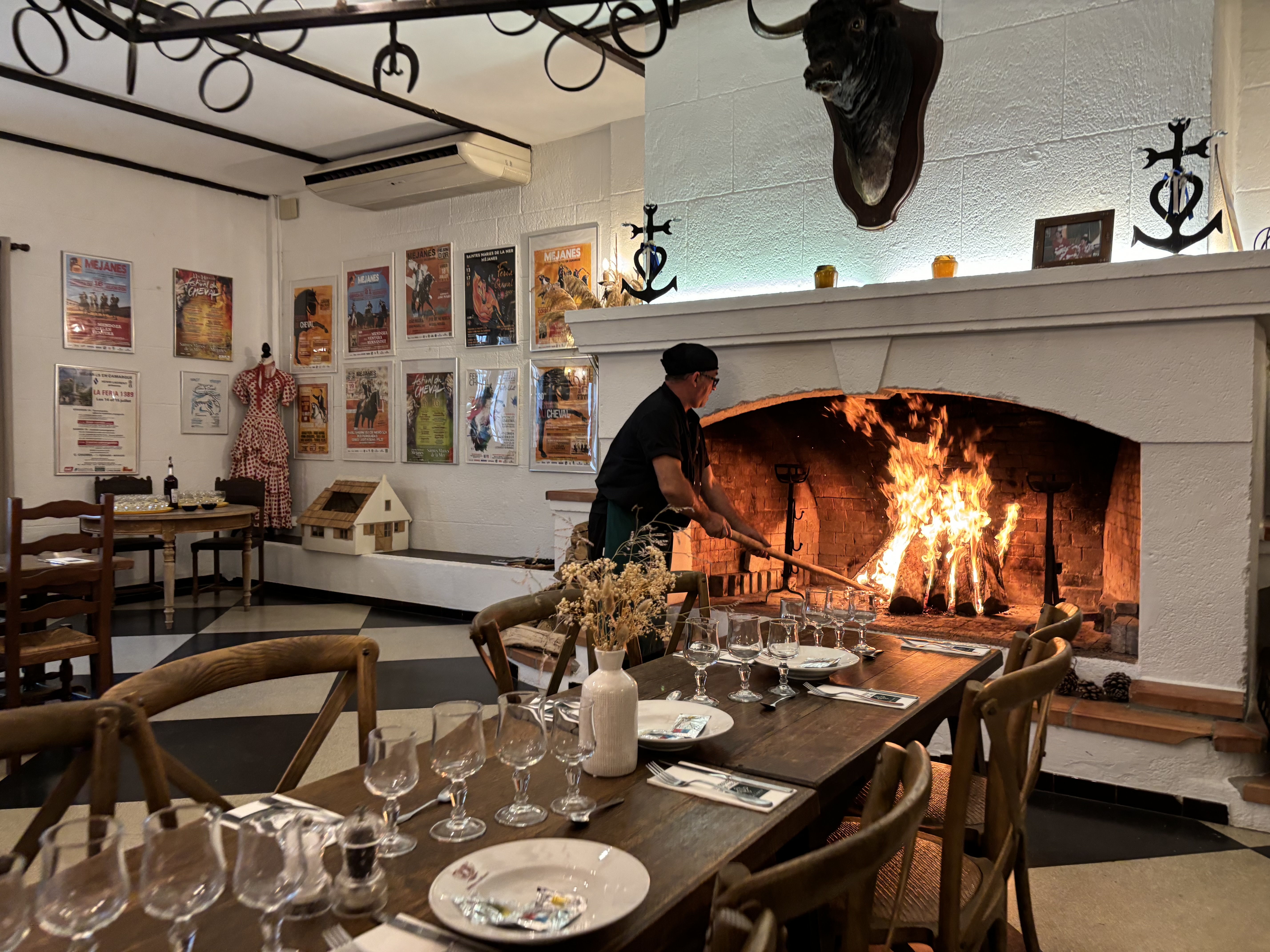 La salle espagnole de La Bergerie de Méjanes, tables dressées et feu dans la grande cheminée.